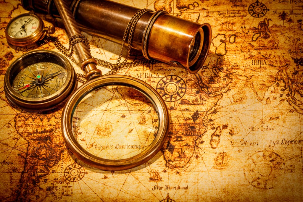 Vintage magnifying glass lies on an ancient world map - Captivating History